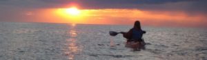 solo kayaker looking at sunset