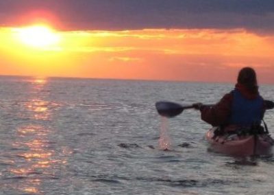 solo kayaker looking at sunset