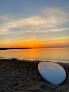 paddle board on beach at sunset