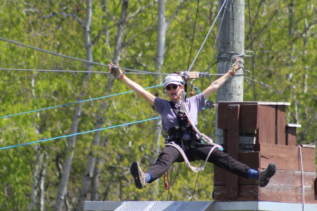 woman riding a zipline through the fields in Door County